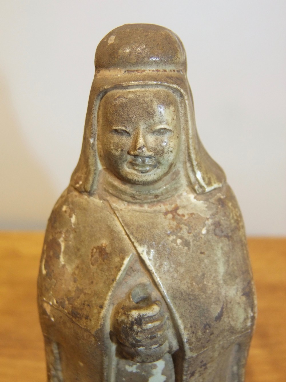 A standing Sui Dynasty earthenware tomb attendant figure featuring draped robes, a tall headpiece, folded hands, and traces of original surface pigments. View V