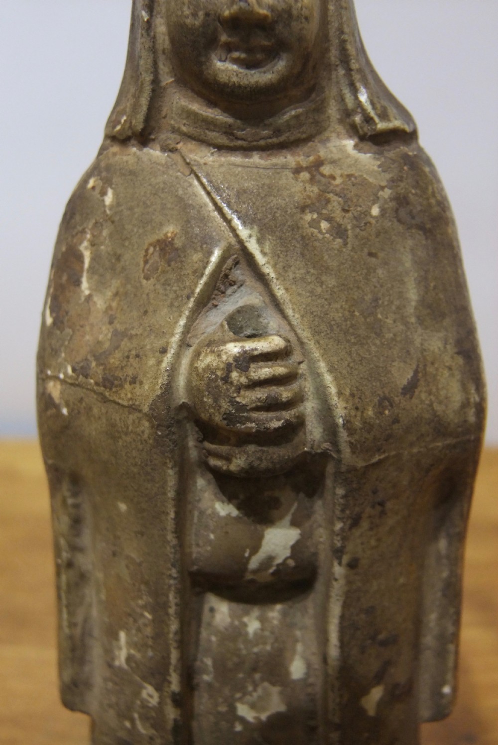 A standing Sui Dynasty earthenware tomb attendant figure featuring draped robes, a tall headpiece, folded hands, and traces of original surface pigments. View VI