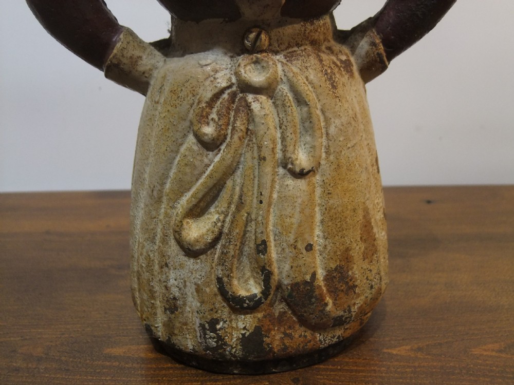 A nineteenth-century painted cast iron money bank depicting a standing figure with hands on hips wearing a red top and cream apron. View VIII