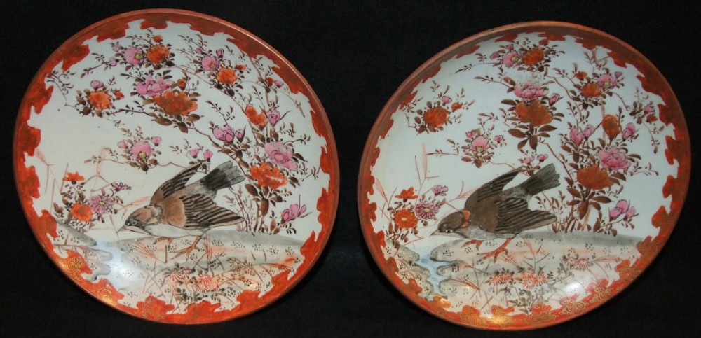 A pair of circular Japanese Kutani porcelain plates decorated with hand-painted sparrows, floral branches, and iron-red gilt borders.