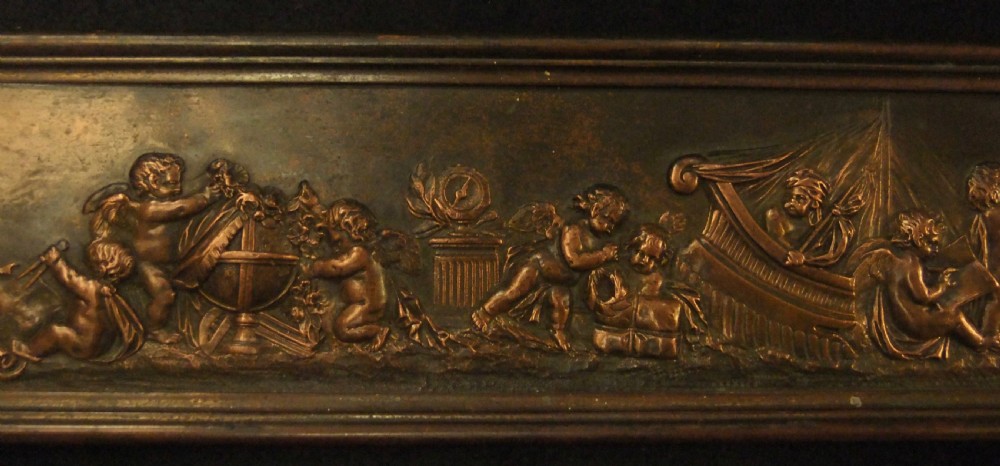A long horizontal dark bronze relief frieze featuring classical cherubs engaged in allegorical scenes set within a slender rectangular frame. View III