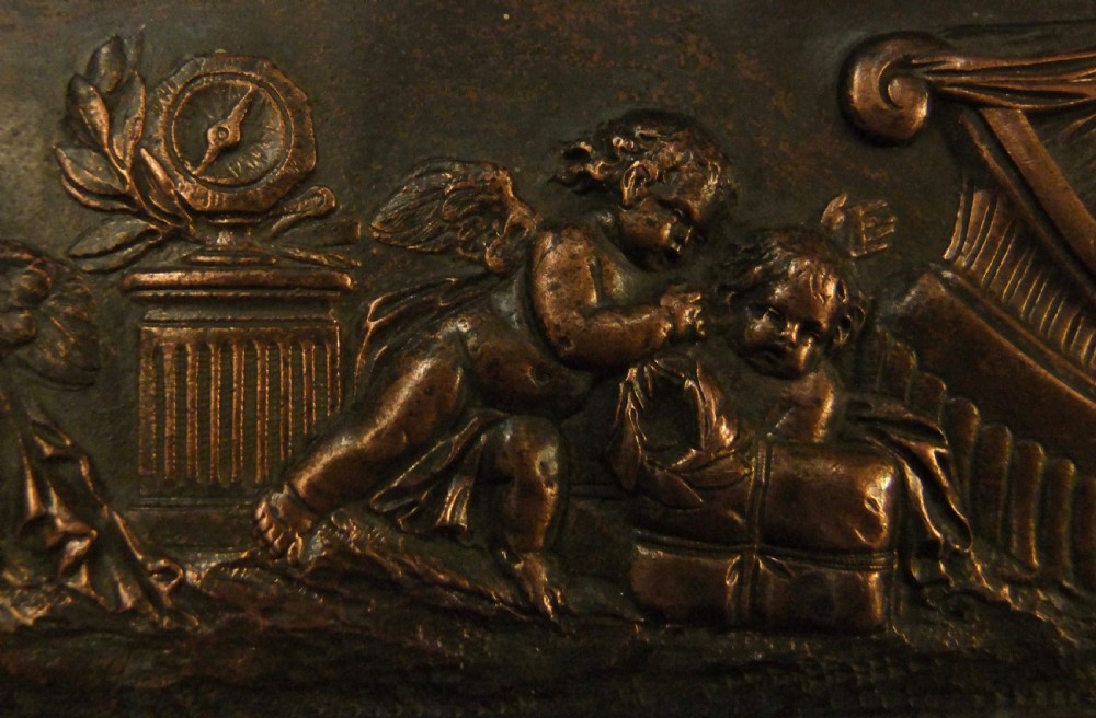 A long horizontal dark bronze relief frieze featuring classical cherubs engaged in allegorical scenes set within a slender rectangular frame. View VIII
