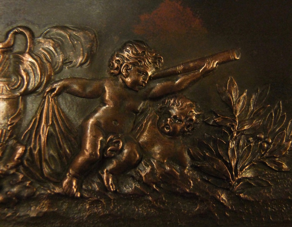 A long horizontal dark bronze relief frieze featuring classical cherubs engaged in allegorical scenes set within a slender rectangular frame. View XI