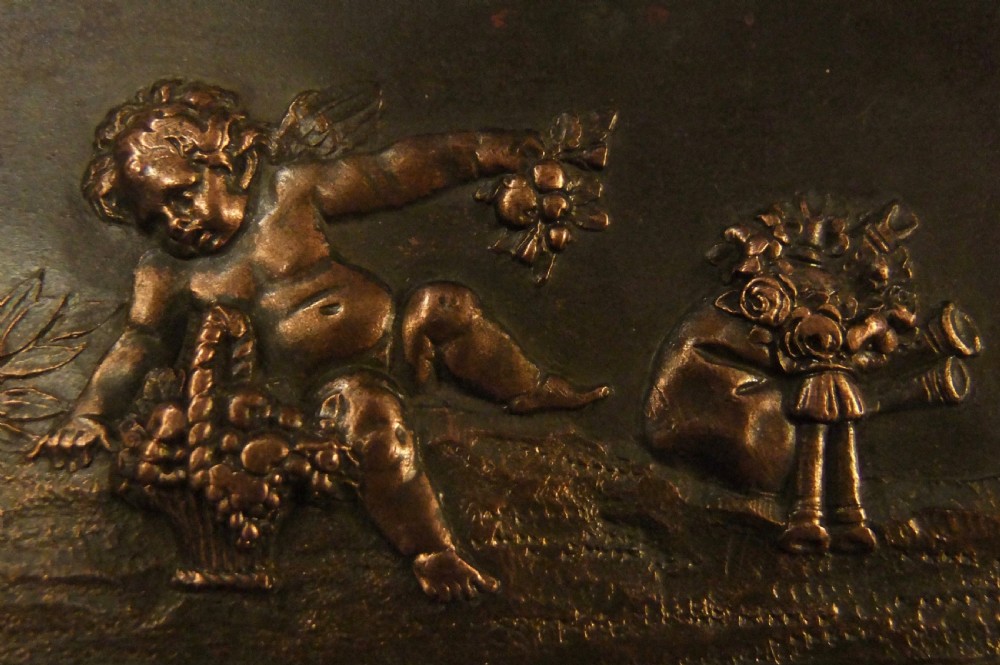 A long horizontal dark bronze relief frieze featuring classical cherubs engaged in allegorical scenes set within a slender rectangular frame. View XII