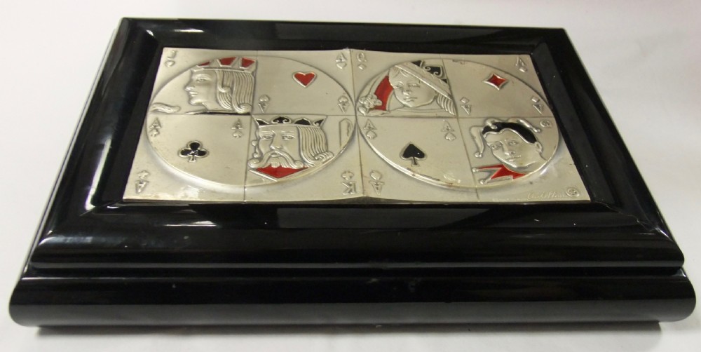 A rectangular black lacquer box featuring an inset silver and enamel lid panel depicting playing card faces and suit motifs.