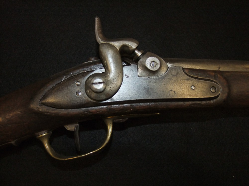 A mid-19th-century French percussion carbine featuring a dark walnut stock, brass fittings, a steel barrel, and an attached socket bayonet against a black background. View III