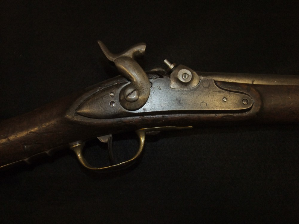 A mid-19th-century French percussion carbine featuring a dark walnut stock, brass fittings, a steel barrel, and an attached socket bayonet against a black background. View IV