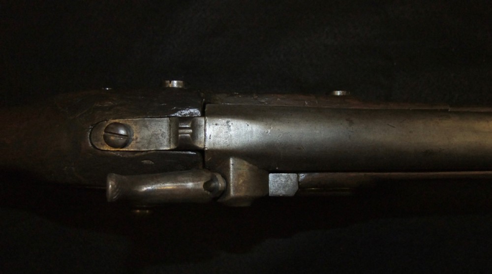 A mid-19th-century French percussion carbine featuring a dark walnut stock, brass fittings, a steel barrel, and an attached socket bayonet against a black background. View VI