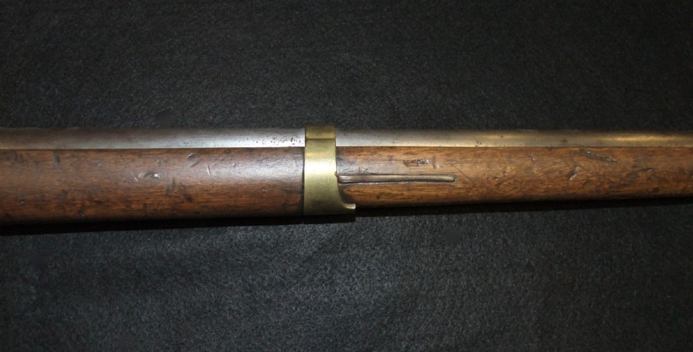 A mid-19th-century French percussion carbine featuring a dark walnut stock, brass fittings, a steel barrel, and an attached socket bayonet against a black background. View VII