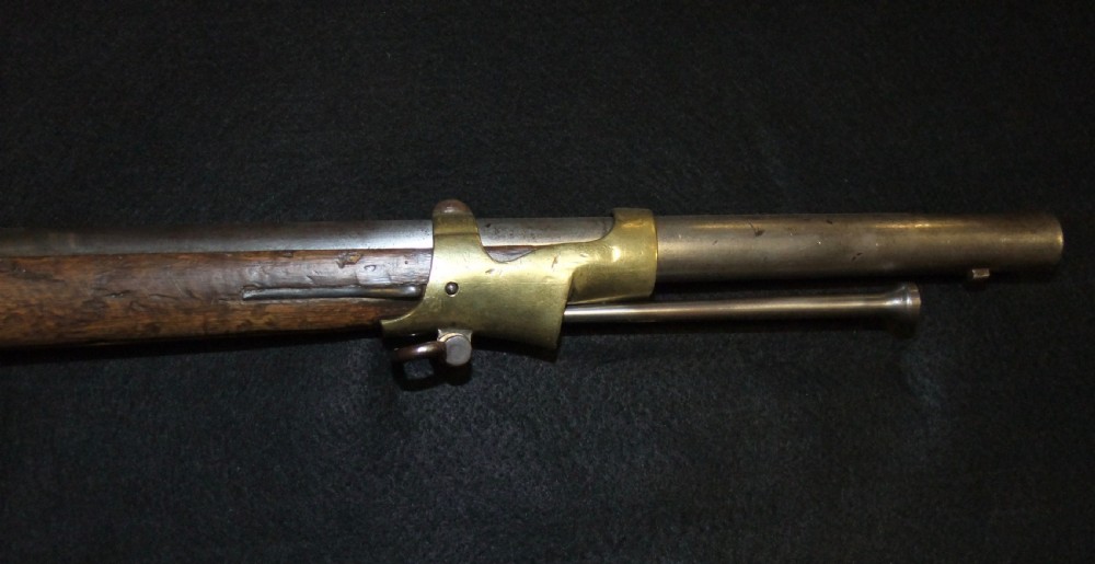 A mid-19th-century French percussion carbine featuring a dark walnut stock, brass fittings, a steel barrel, and an attached socket bayonet against a black background. View VIII