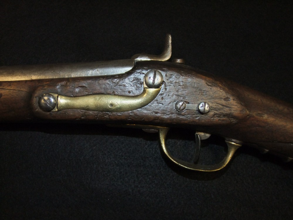 A mid-19th-century French percussion carbine featuring a dark walnut stock, brass fittings, a steel barrel, and an attached socket bayonet against a black background. View IX
