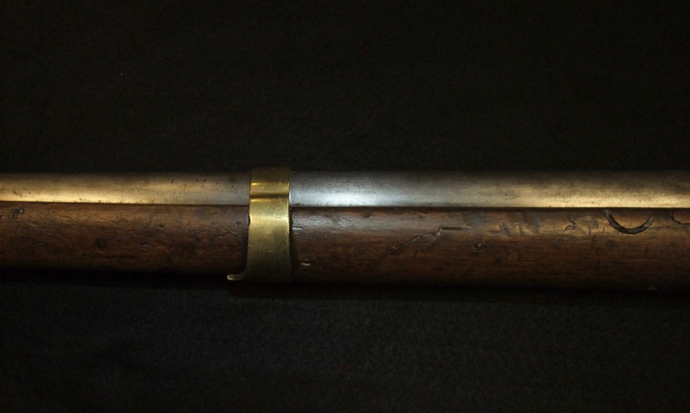 A mid-19th-century French percussion carbine featuring a dark walnut stock, brass fittings, a steel barrel, and an attached socket bayonet against a black background. View XI