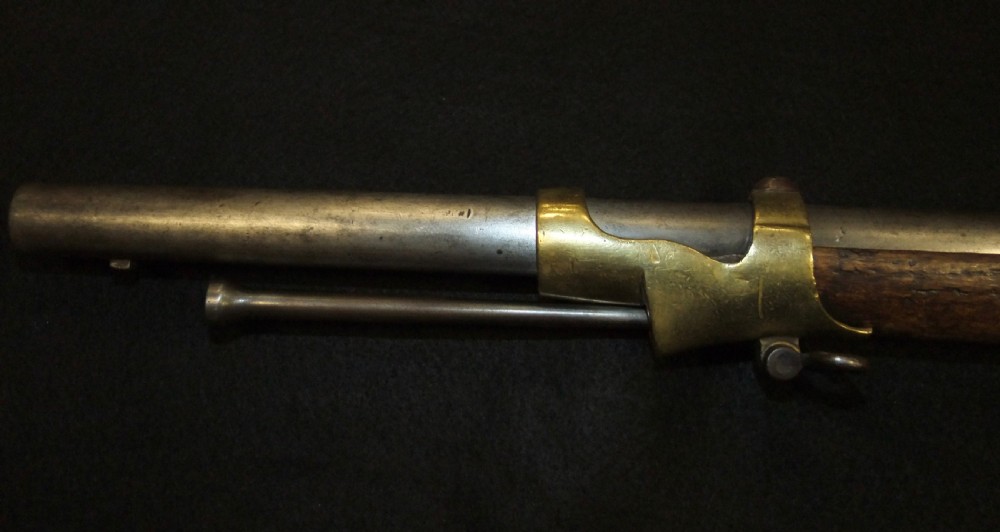 A mid-19th-century French percussion carbine featuring a dark walnut stock, brass fittings, a steel barrel, and an attached socket bayonet against a black background. View XII