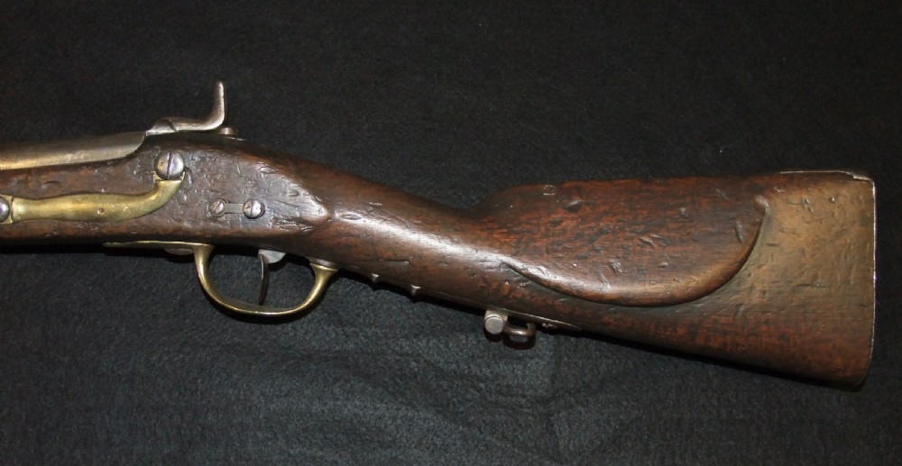 A mid-19th-century French percussion carbine featuring a dark walnut stock, brass fittings, a steel barrel, and an attached socket bayonet against a black background. View XV
