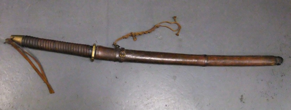 A Japanese WWII officers Shin-Gunto katana featuring a leather-wrapped scabbard, ribbed handle, and brass tsuba.
