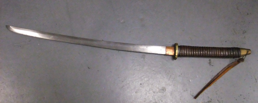 A Japanese WWII officers Shin-Gunto katana featuring a leather-wrapped scabbard, ribbed handle, and brass tsuba. View IV