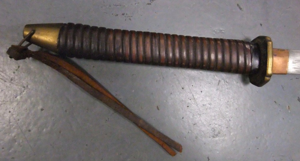 A Japanese WWII officers Shin-Gunto katana featuring a leather-wrapped scabbard, ribbed handle, and brass tsuba. View V