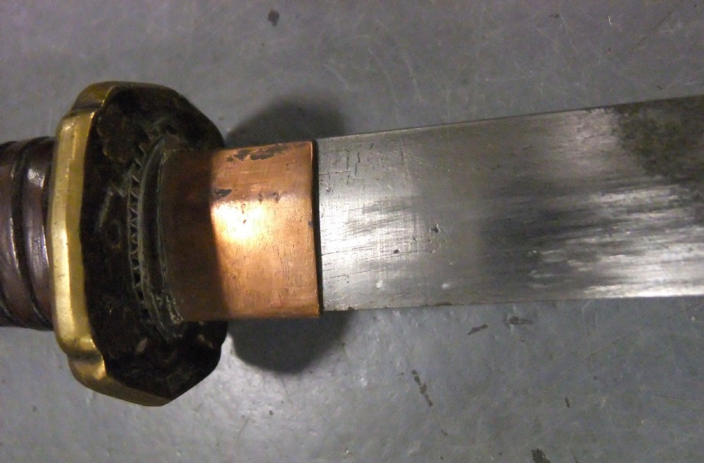 A Japanese WWII officers Shin-Gunto katana featuring a leather-wrapped scabbard, ribbed handle, and brass tsuba. View VIII