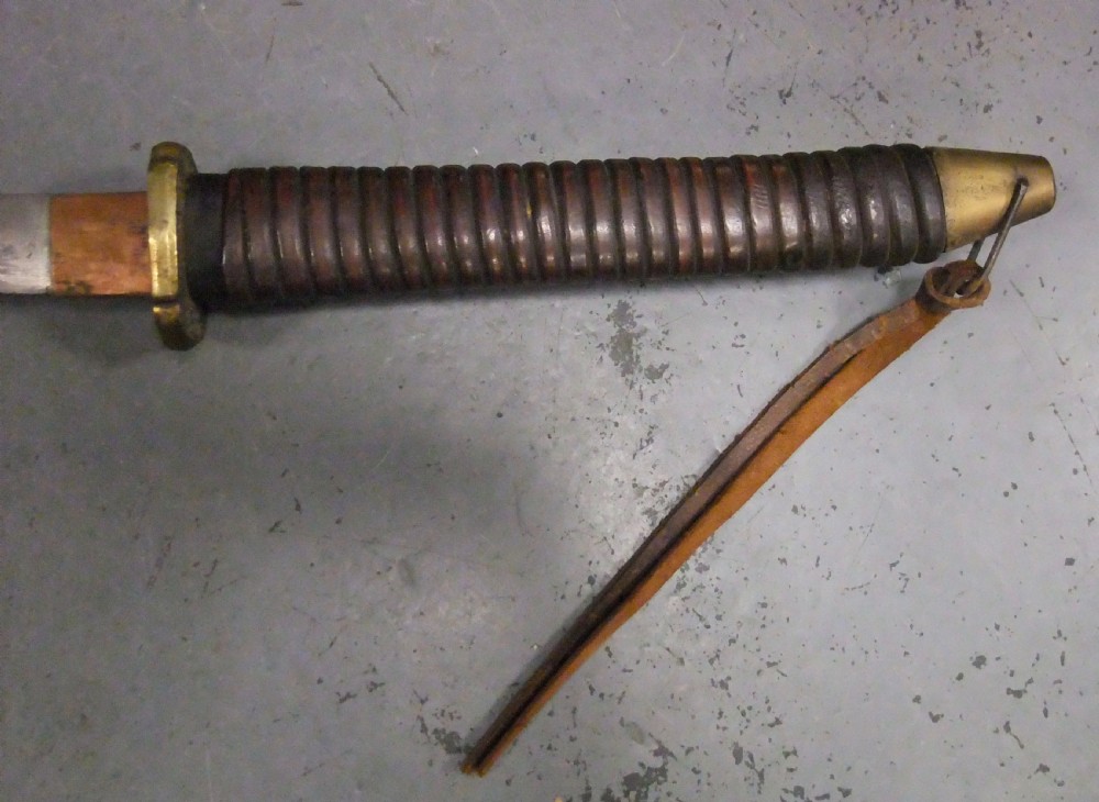 A Japanese WWII officers Shin-Gunto katana featuring a leather-wrapped scabbard, ribbed handle, and brass tsuba. View IX