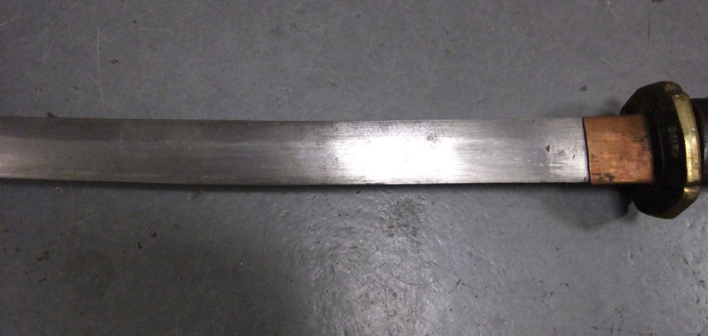 A Japanese WWII officers Shin-Gunto katana featuring a leather-wrapped scabbard, ribbed handle, and brass tsuba. View XII