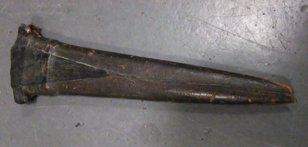 An antique Indian Katar push dagger featuring a dark iron H-shaped handle with double crossbars beside its tapered leather scabbard. View XIII