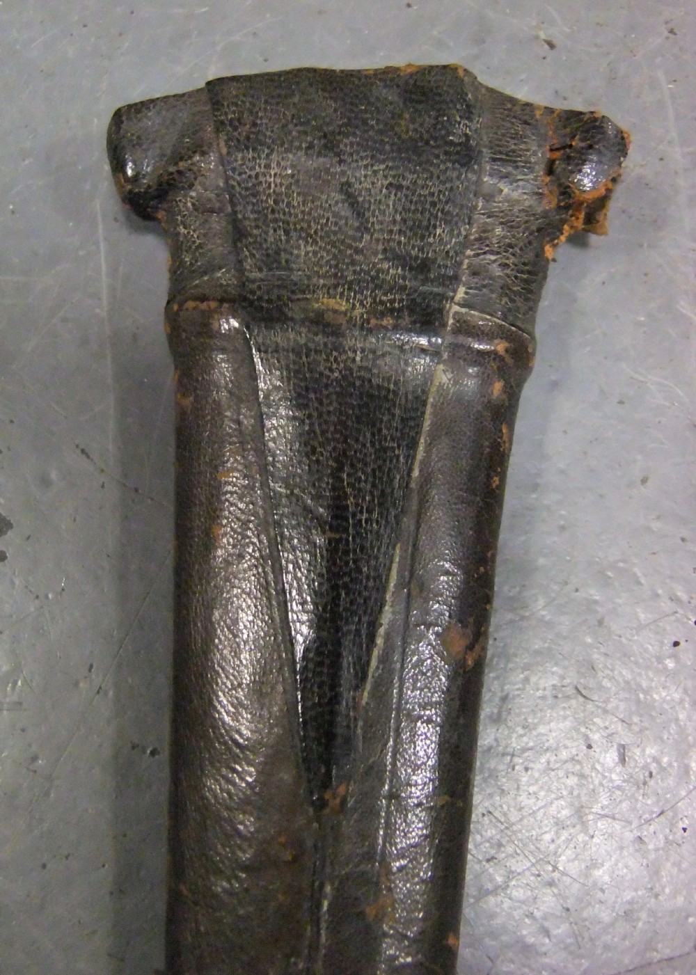An antique Indian Katar push dagger featuring a dark iron H-shaped handle with double crossbars beside its tapered leather scabbard. View XIV