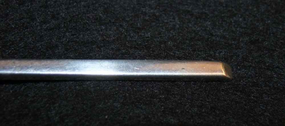 A solid silver spoon featuring a rounded fig-shaped bowl and a straight stem with an obliquely cut slip top end against a dark background. View IV