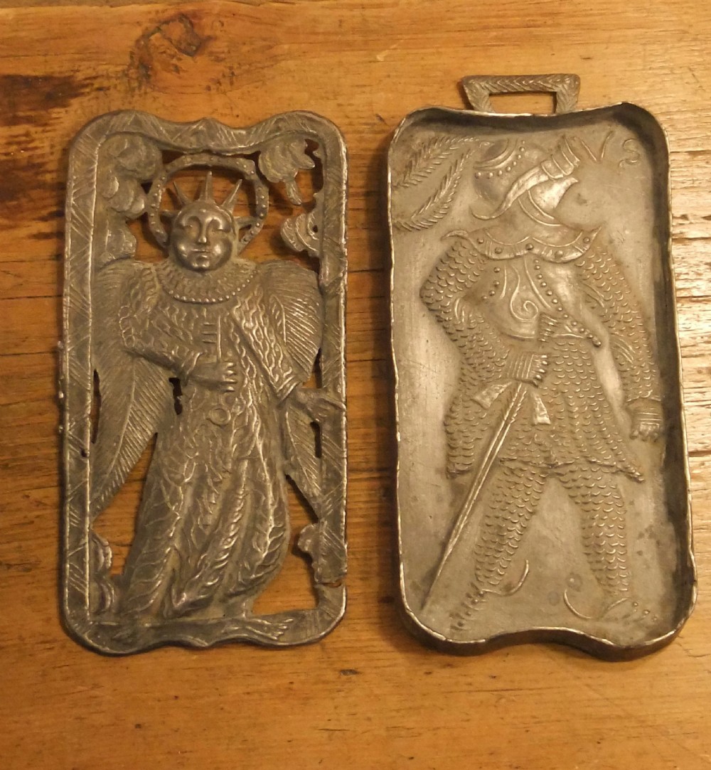 A grey lead alloy hinged diptych panel featuring a crude relief casting of a haloed figure holding a key alongside a companion panel with pseudo-medieval inscriptions. View II