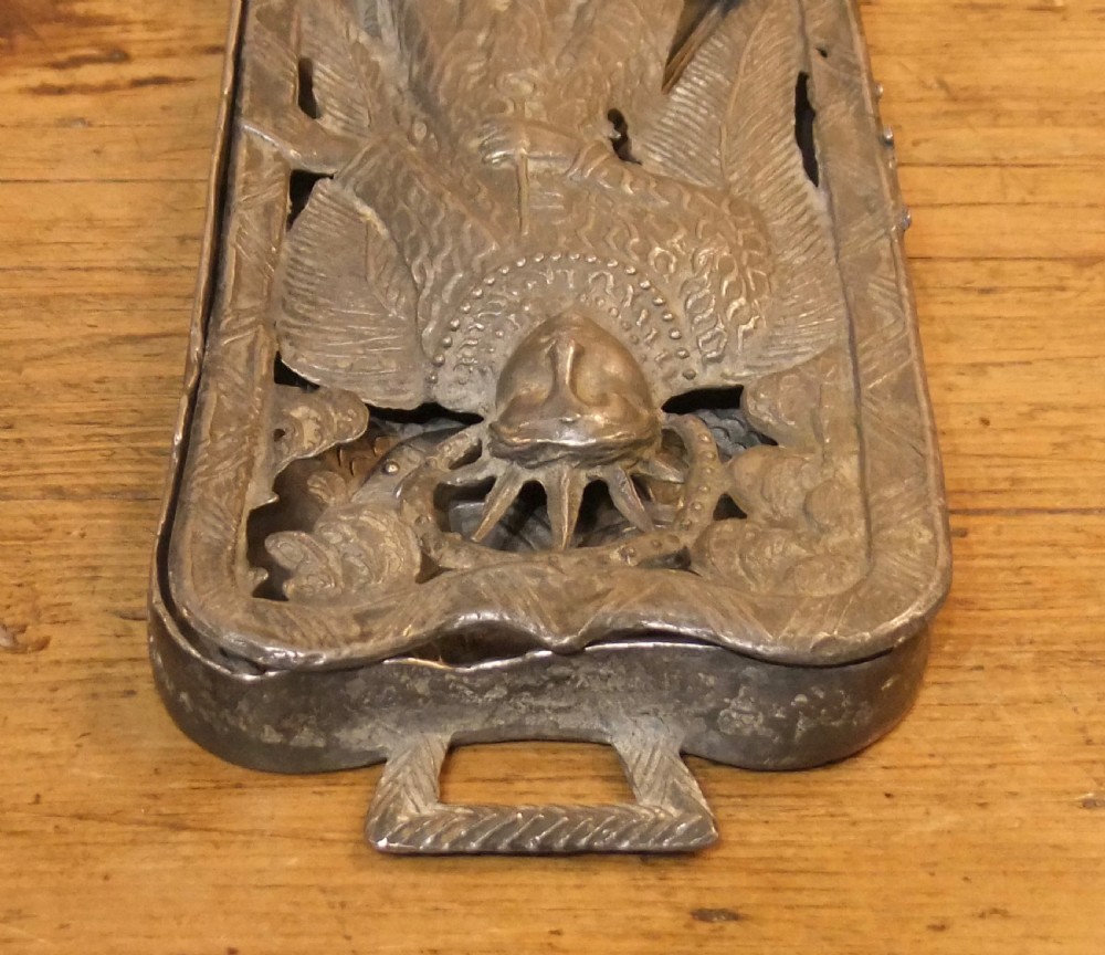 A grey lead alloy hinged diptych panel featuring a crude relief casting of a haloed figure holding a key alongside a companion panel with pseudo-medieval inscriptions. View V