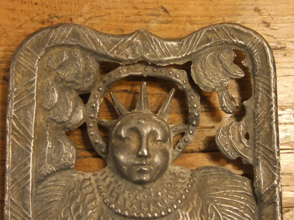 A grey lead alloy hinged diptych panel featuring a crude relief casting of a haloed figure holding a key alongside a companion panel with pseudo-medieval inscriptions. View VII