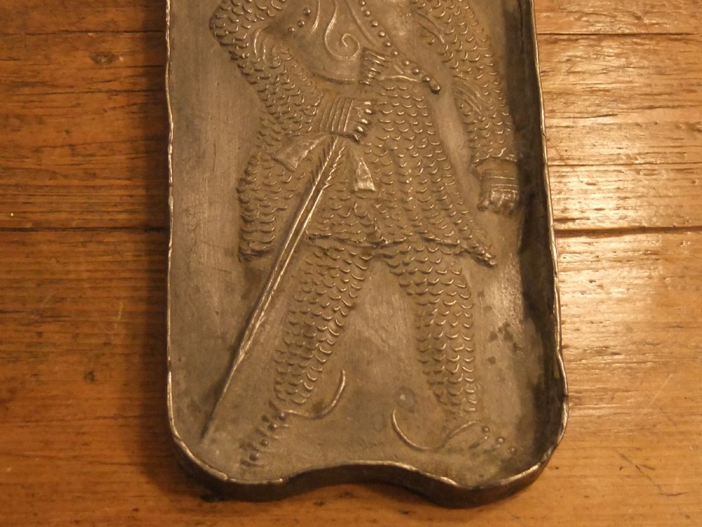 A grey lead alloy hinged diptych panel featuring a crude relief casting of a haloed figure holding a key alongside a companion panel with pseudo-medieval inscriptions. View XII