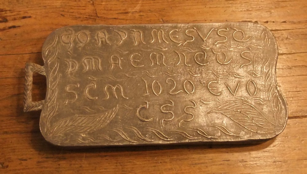 A grey lead alloy hinged diptych panel featuring a crude relief casting of a haloed figure holding a key alongside a companion panel with pseudo-medieval inscriptions. View XIII