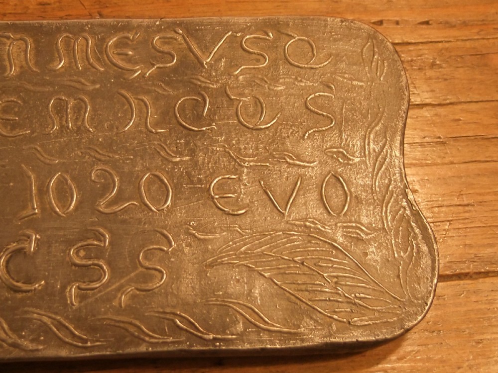 A grey lead alloy hinged diptych panel featuring a crude relief casting of a haloed figure holding a key alongside a companion panel with pseudo-medieval inscriptions. View XV