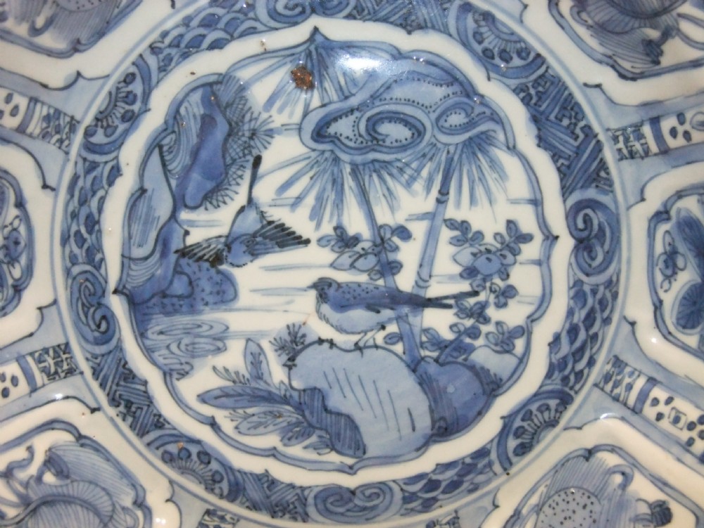 A Chinese Wanli Kraak porcelain deep plate decorated in underglaze blue with central birds and plants surrounded by a panelled rim with a scalloped edge. View II