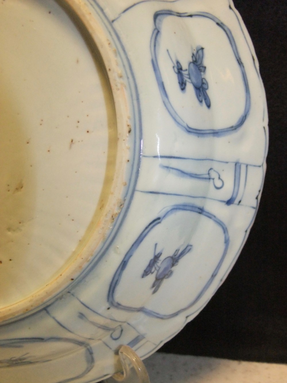 A Chinese Wanli Kraak porcelain deep plate decorated in underglaze blue with central birds and plants surrounded by a panelled rim with a scalloped edge. View X