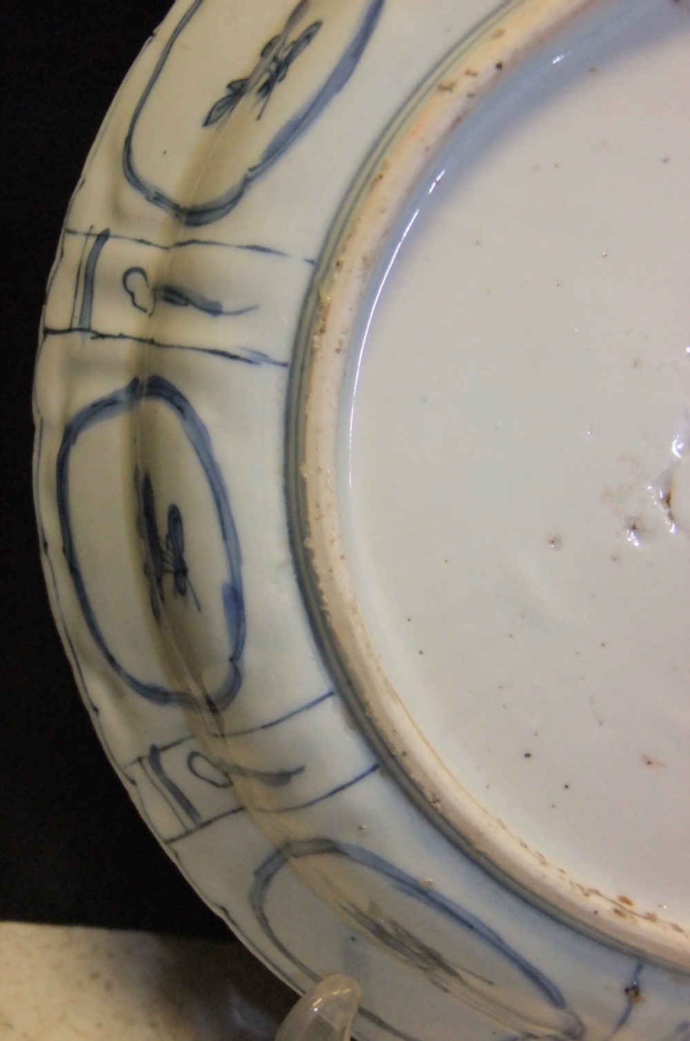 A Chinese Wanli Kraak porcelain deep plate decorated in underglaze blue with central birds and plants surrounded by a panelled rim with a scalloped edge. View XI