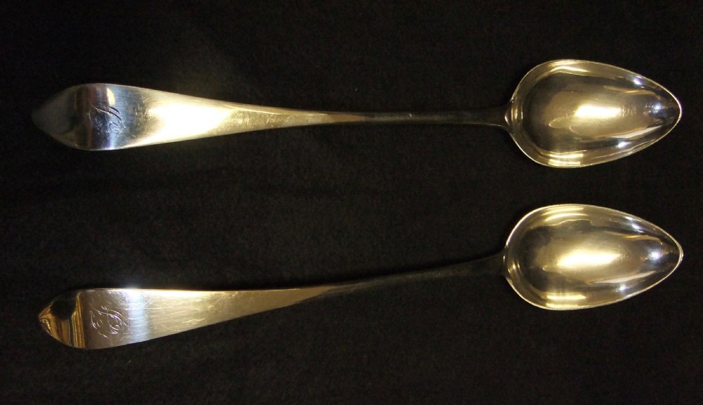 A pair of polished sterling silver George III Scottish basting spoons featuring pointed handles with subtle engraved monograms.