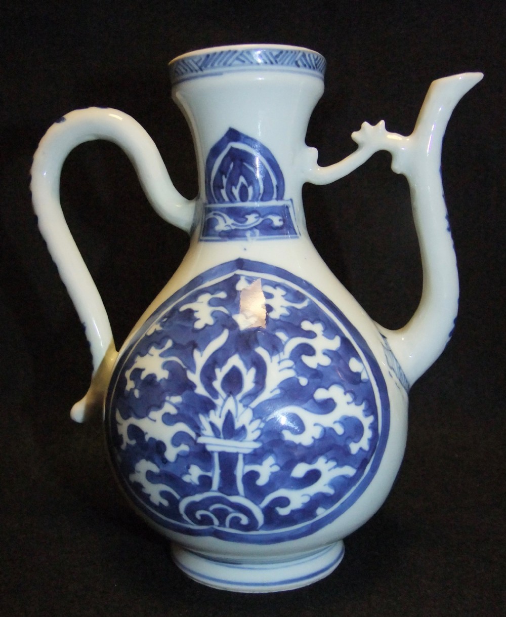 A blue and white Chinese porcelain wine ewer featuring an elongated curved handle, a tall spout with a connecting strut, and painted floral medallion motifs. View VI