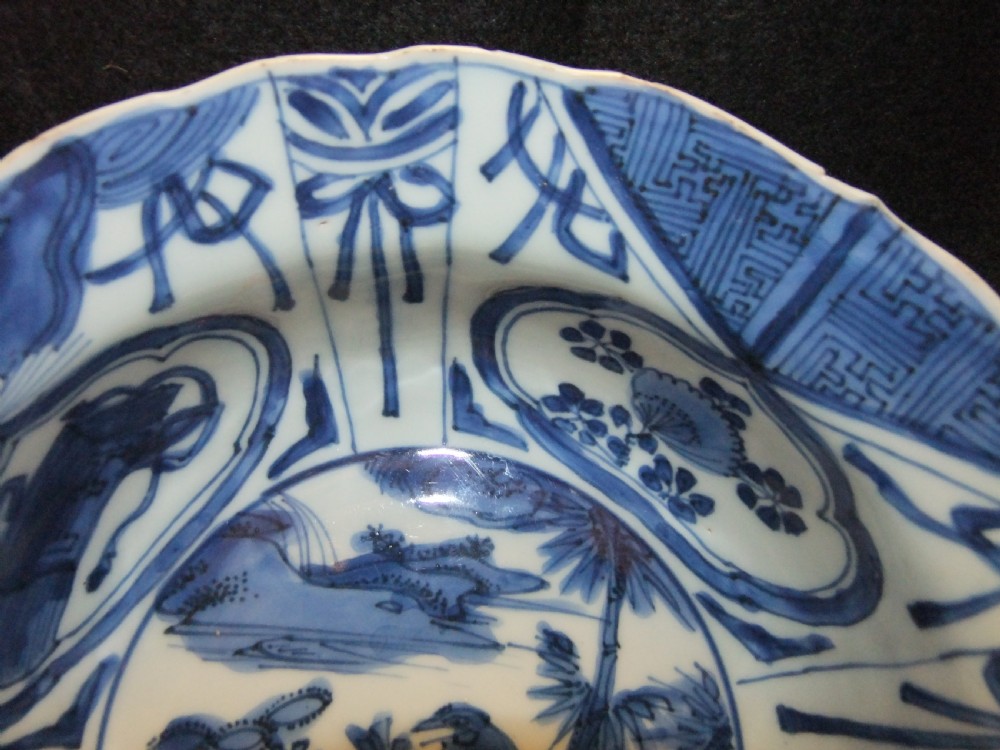 A circular Wanli period Kraak porcelain klapmuts bowl decorated with cobalt blue underglaze landscapes and panelled rim motifs. View III