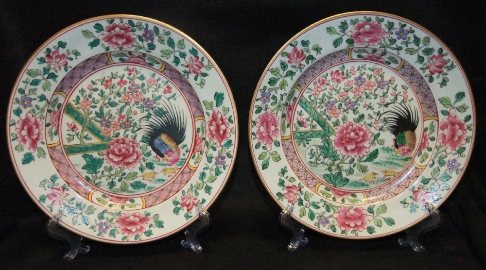 A pair of circular Chinese export porcelain plates decorated with hand-painted roosters, peonies, and pink and green floral borders.