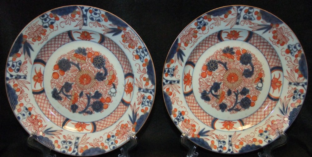 A pair of circular Japanese Edo Period Imari porcelain plates featuring intricate floral motifs in underglaze blue, iron red, and gold gilding on a white ground.