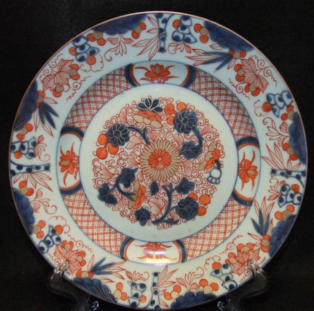 A pair of circular Japanese Edo Period Imari porcelain plates featuring intricate floral motifs in underglaze blue, iron red, and gold gilding on a white ground. View II