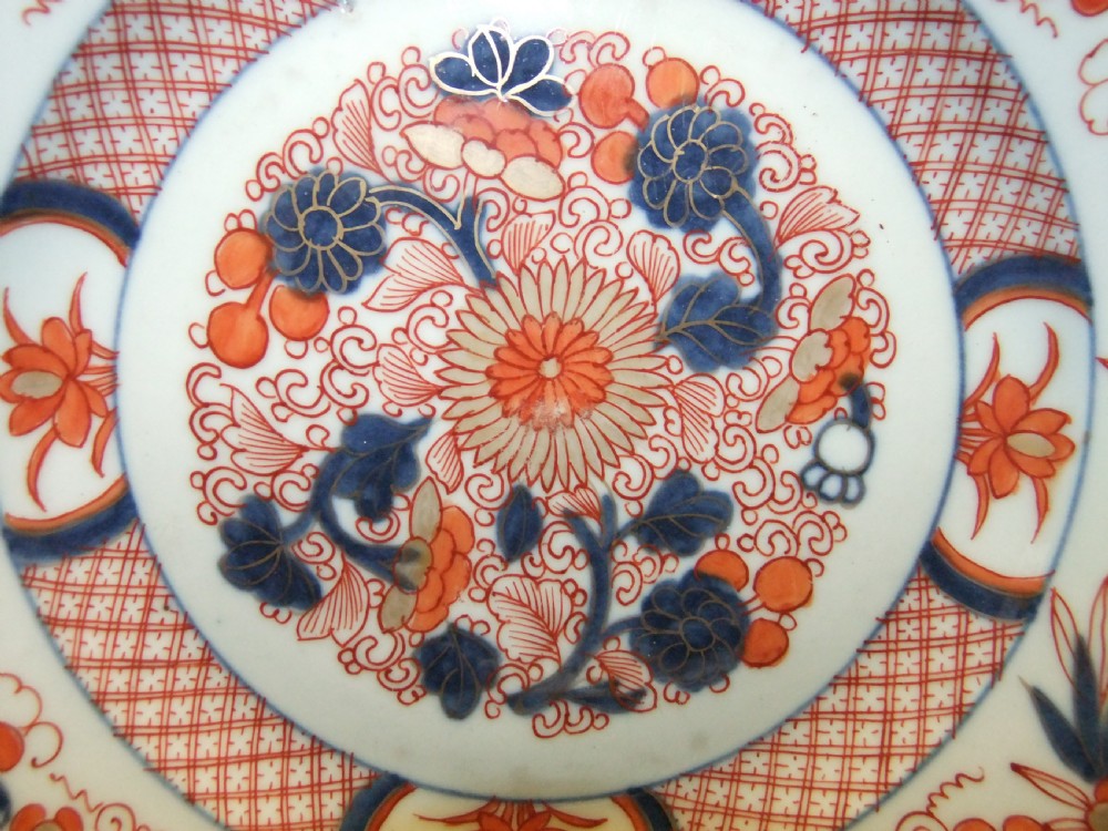 A pair of circular Japanese Edo Period Imari porcelain plates featuring intricate floral motifs in underglaze blue, iron red, and gold gilding on a white ground. View III