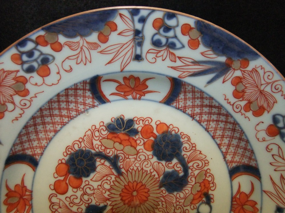 A pair of circular Japanese Edo Period Imari porcelain plates featuring intricate floral motifs in underglaze blue, iron red, and gold gilding on a white ground. View IV
