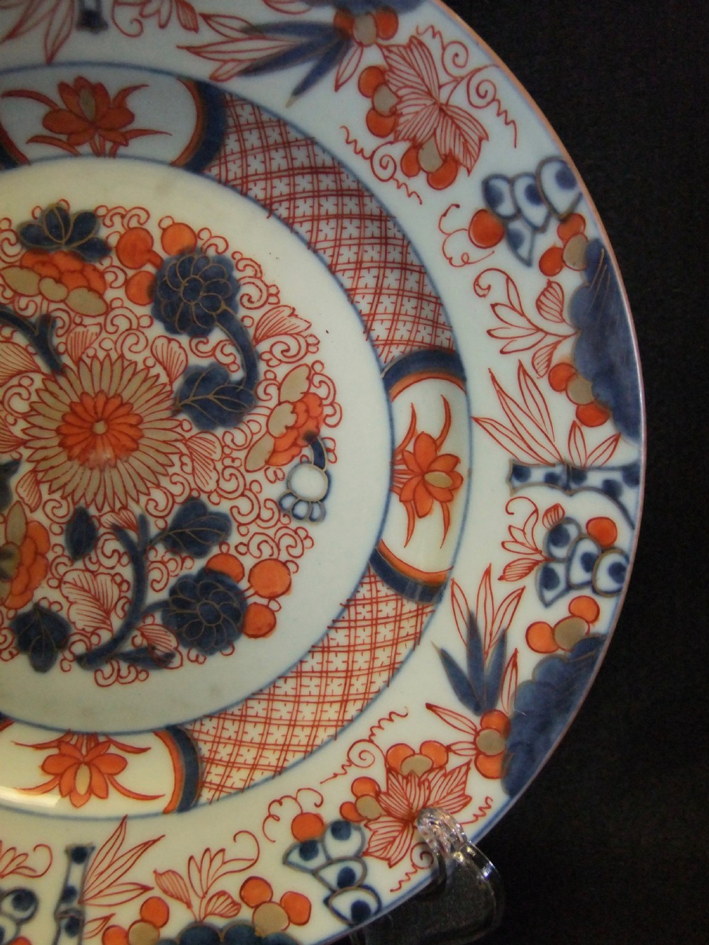 A pair of circular Japanese Edo Period Imari porcelain plates featuring intricate floral motifs in underglaze blue, iron red, and gold gilding on a white ground. View V
