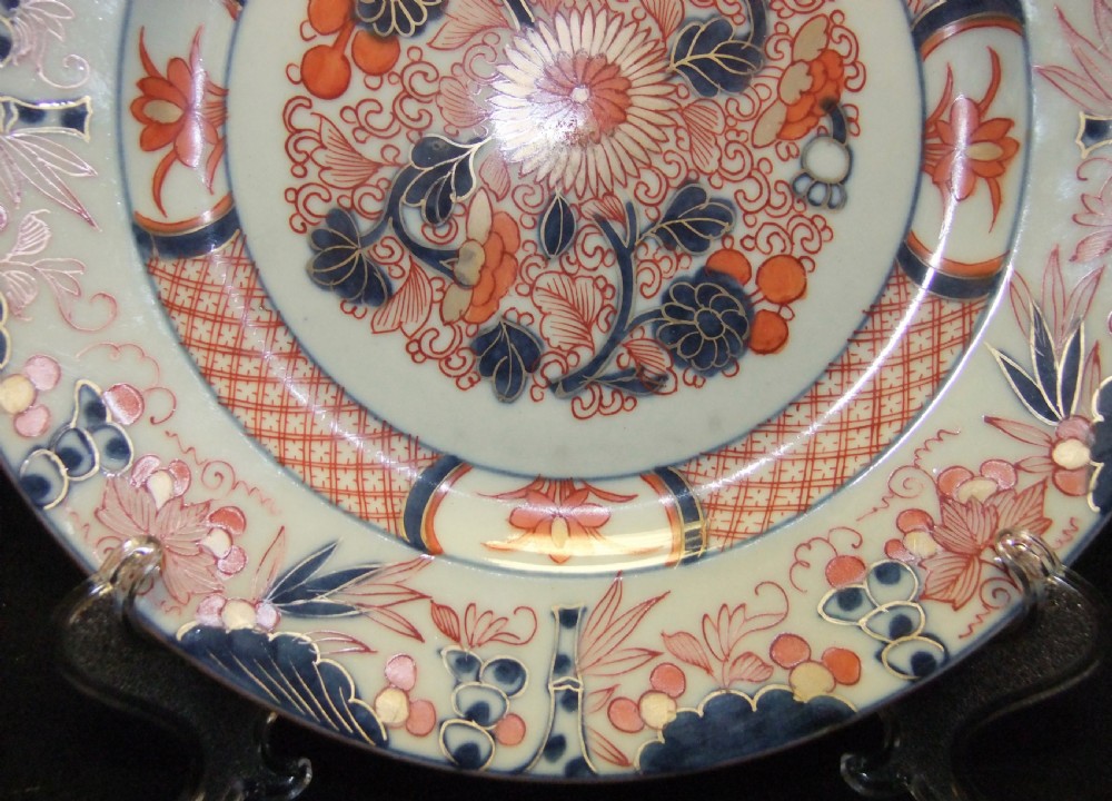 A pair of circular Japanese Edo Period Imari porcelain plates featuring intricate floral motifs in underglaze blue, iron red, and gold gilding on a white ground. View VI