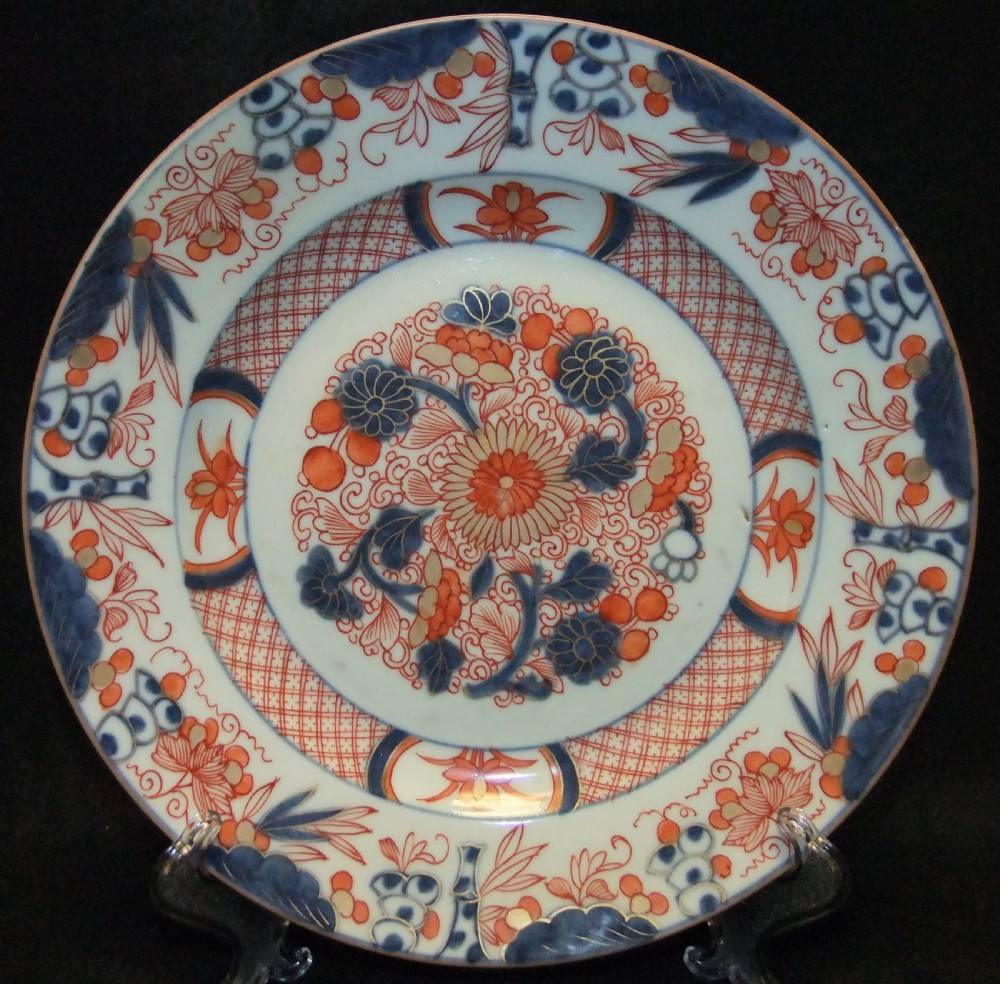 A pair of circular Japanese Edo Period Imari porcelain plates featuring intricate floral motifs in underglaze blue, iron red, and gold gilding on a white ground. View IX