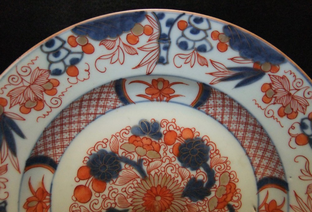 A pair of circular Japanese Edo Period Imari porcelain plates featuring intricate floral motifs in underglaze blue, iron red, and gold gilding on a white ground. View XI