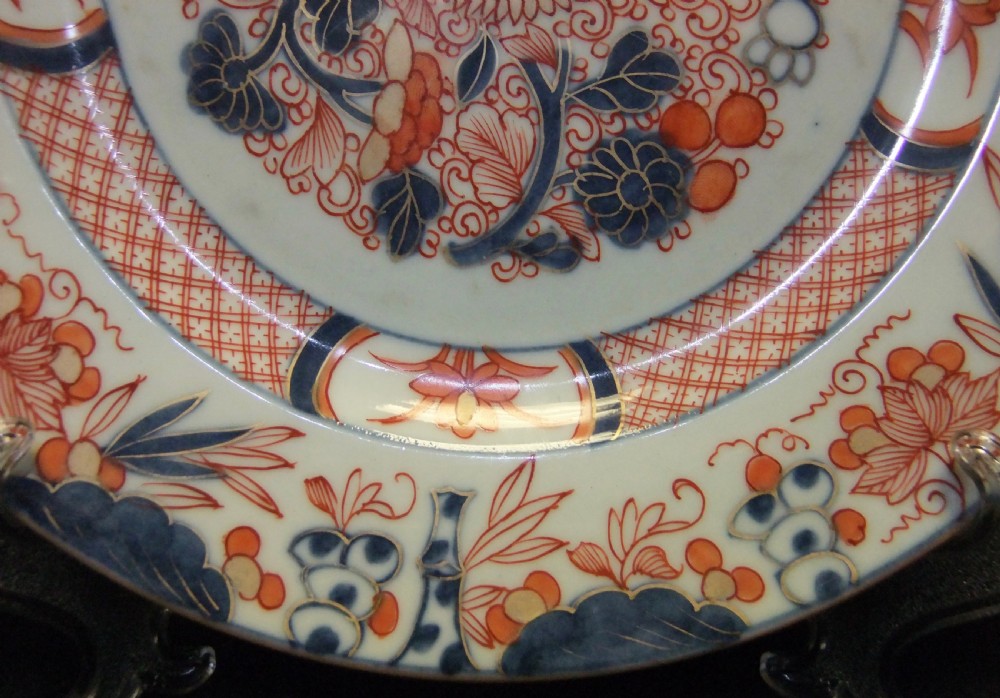 A pair of circular Japanese Edo Period Imari porcelain plates featuring intricate floral motifs in underglaze blue, iron red, and gold gilding on a white ground. View XIII