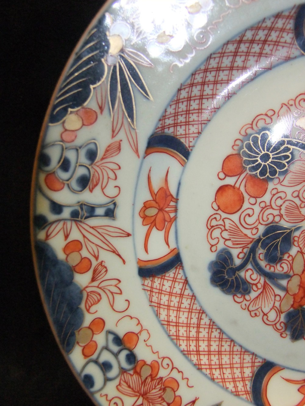 A pair of circular Japanese Edo Period Imari porcelain plates featuring intricate floral motifs in underglaze blue, iron red, and gold gilding on a white ground. View XIV